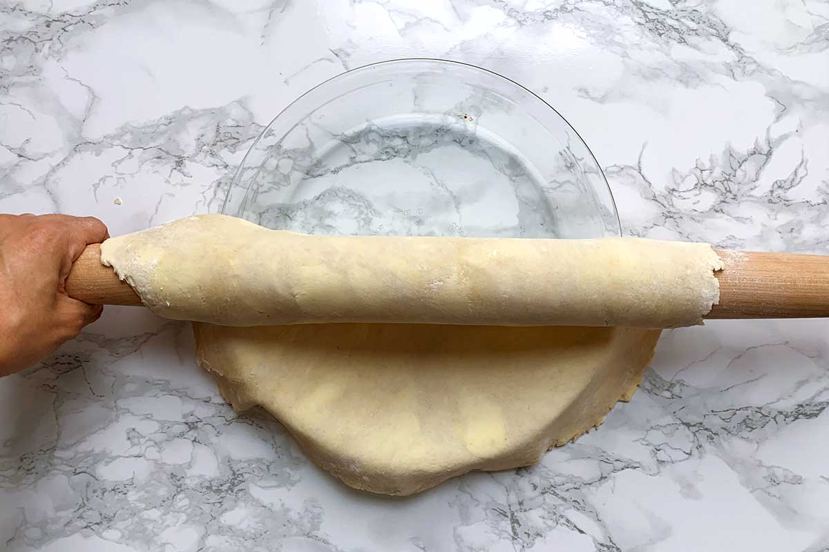 Unrolling dough from rolling pin into pie plate