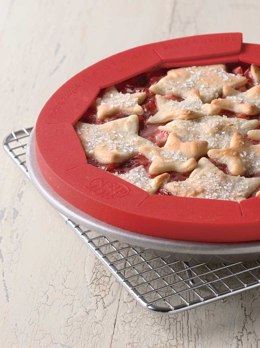 Fruit pie with top crust in star pattern and a pie shield around it