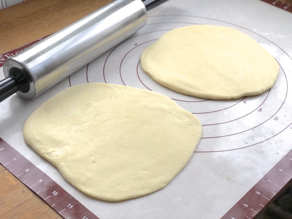 Two round circles of pierogi dough, rolled on a silicone mat