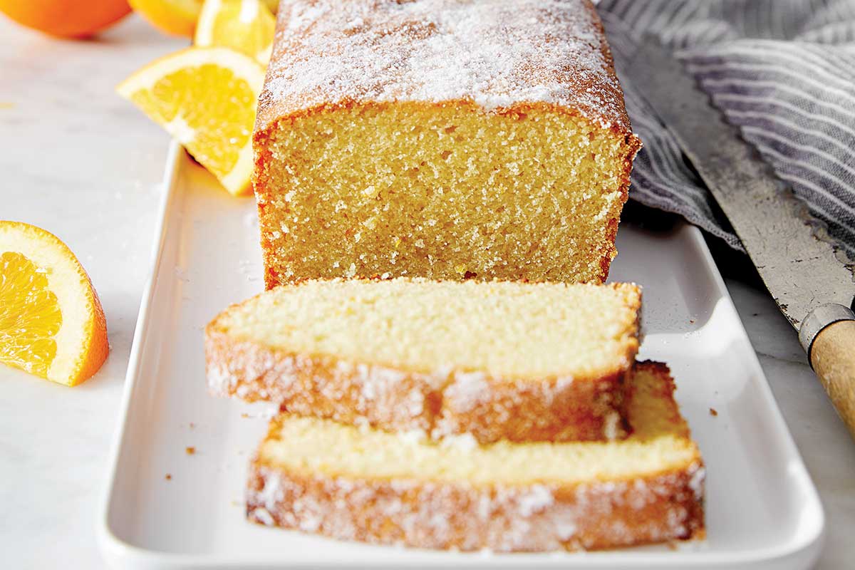 A pound cake on a wooden board cut into slices