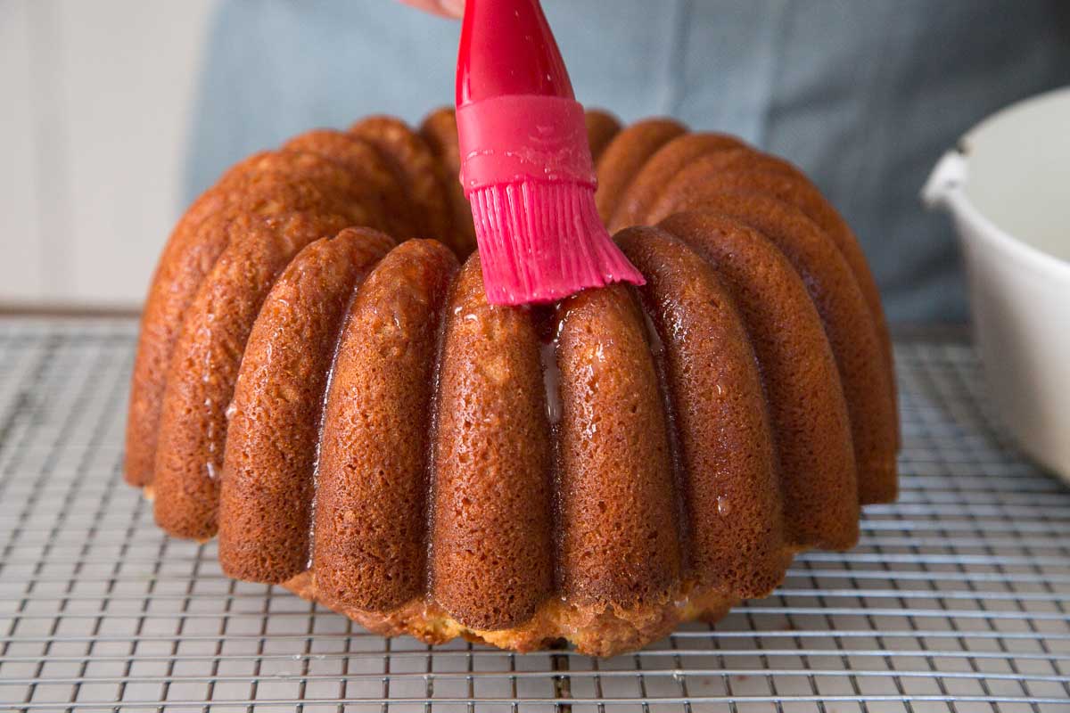 A baker brushing lemon glaze on a pound cake