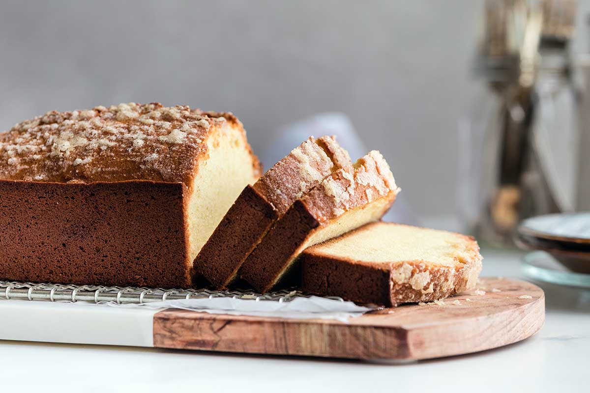 A pound cake on a wooden board cut into slices