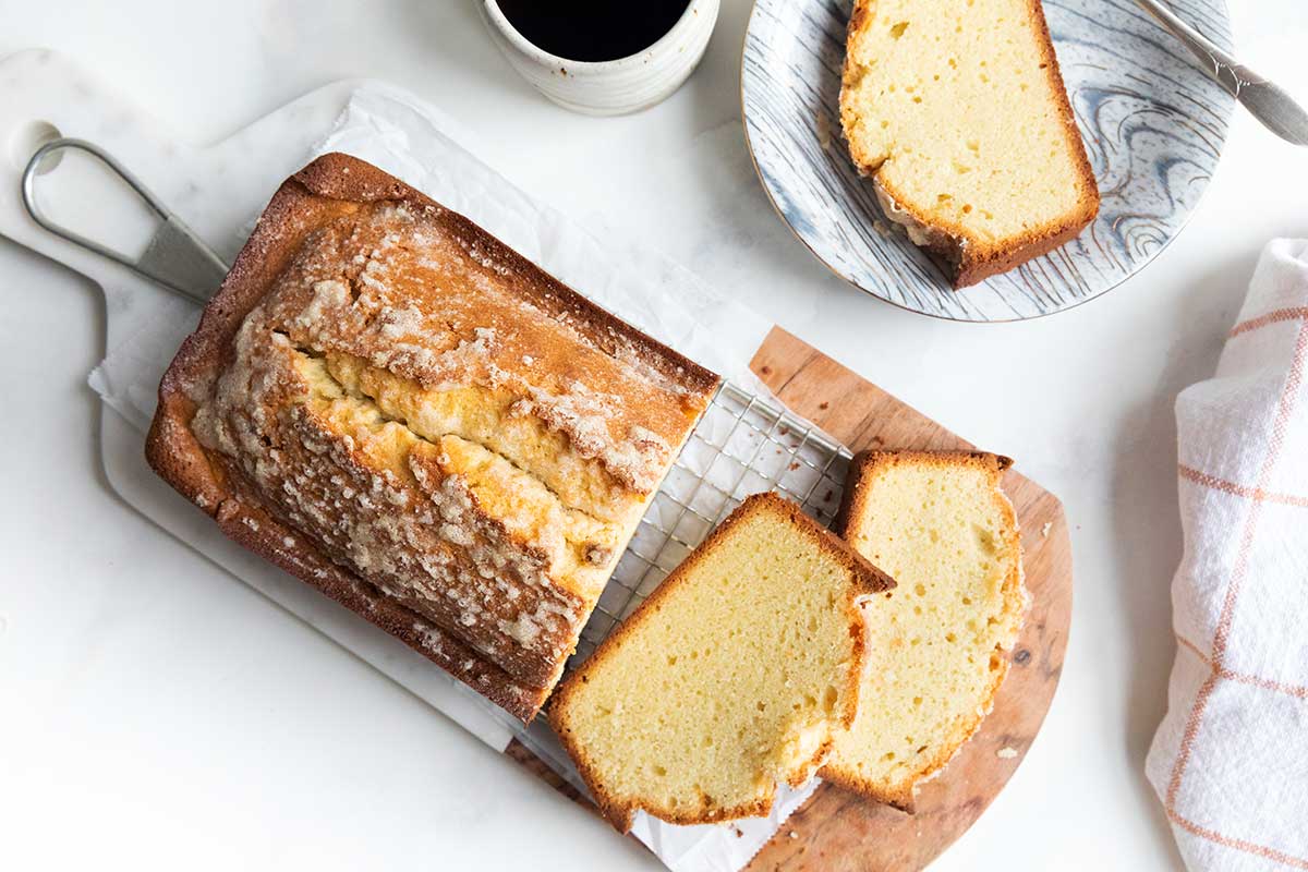 Gluten-free pound cake baked in a loaf pan and cut into slices on a wooden cutting board