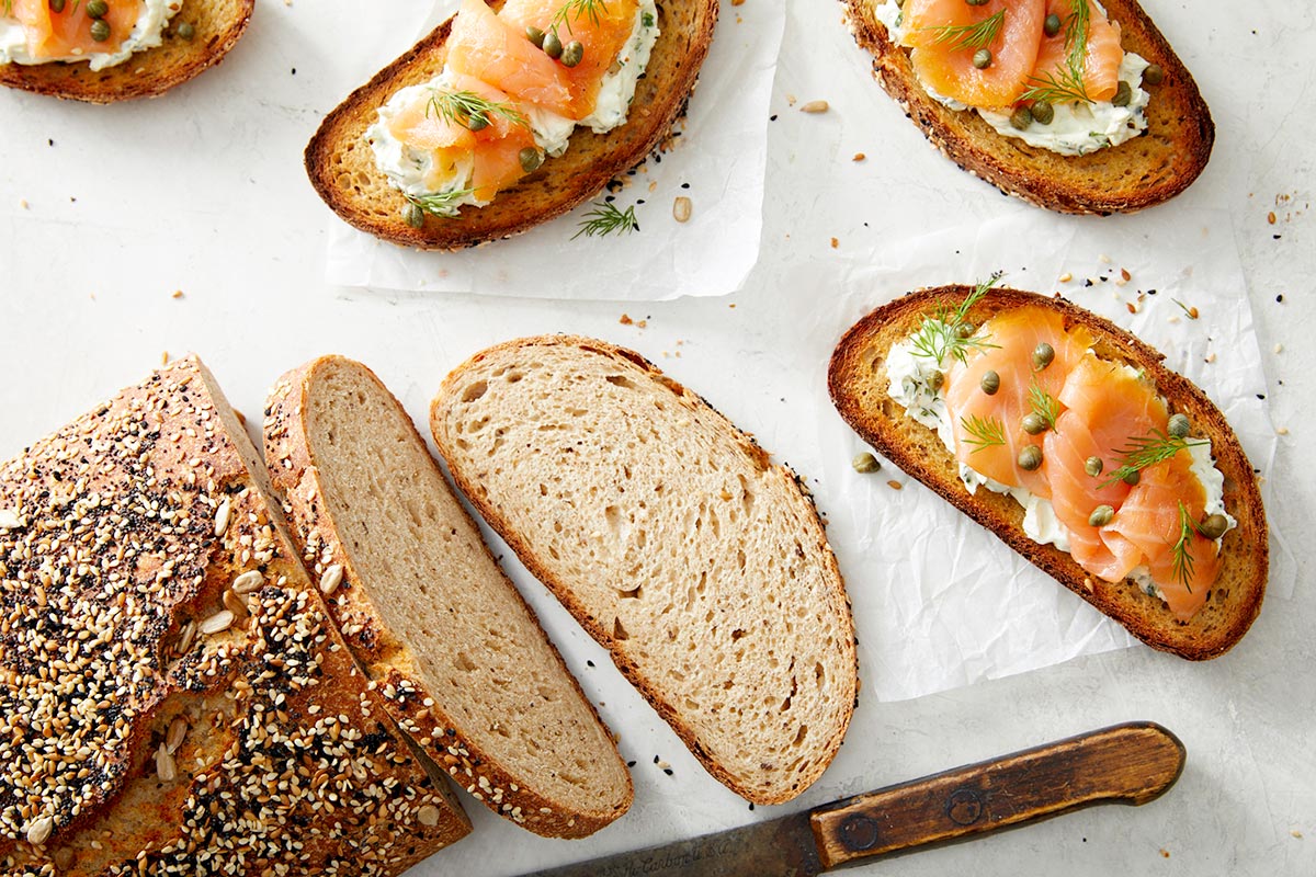 A loaf of pumpernickel rye bread topped with Everything Bagel Topping and lox