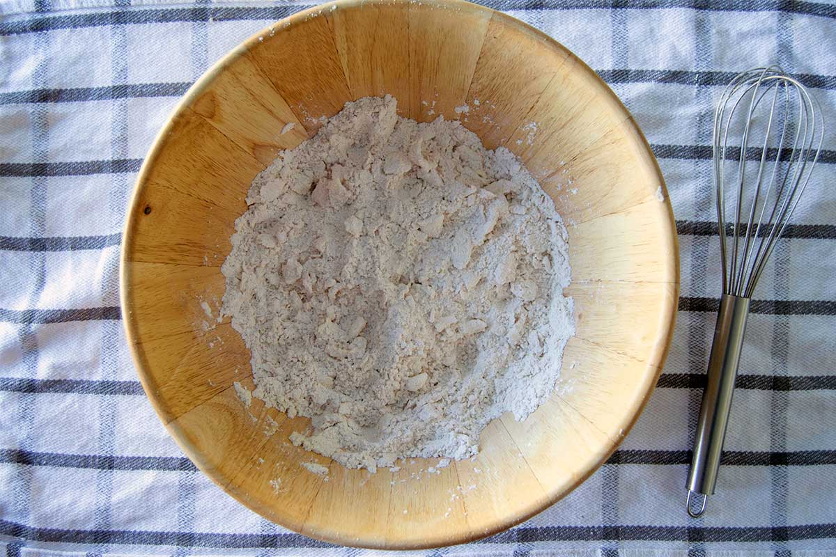 Bowl with butter cut into dry ingredients, showing some large chunks