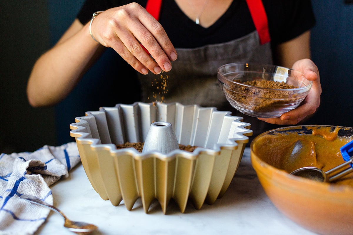 A baker sprinkling the brown sugar-espresso filling over the pumpkin cake batter