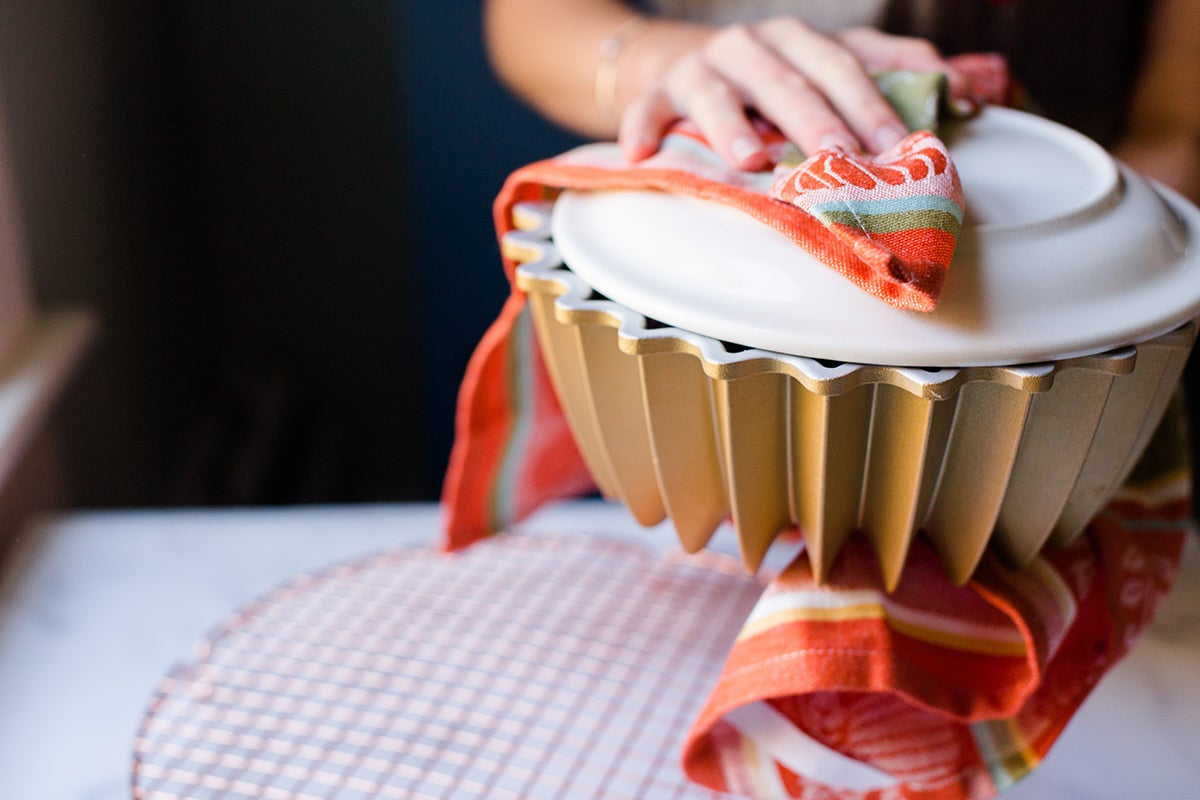 A baker turning a pumpkin Bundt cake out of the pan