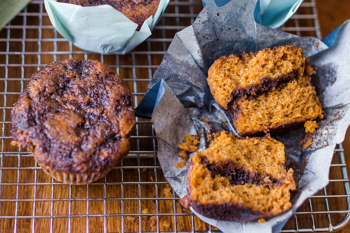 Two pumpkin muffins, one broken open to reveal and espresso swirl inside