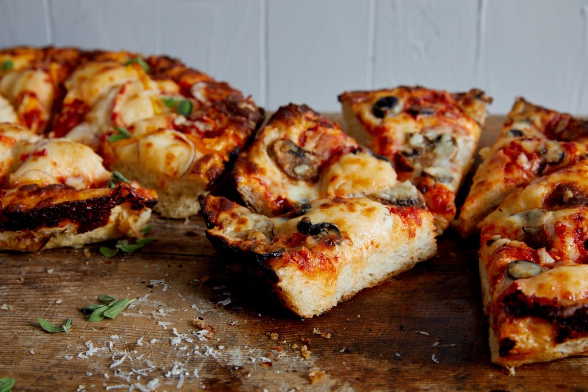 Wedges of thick-crust pizza on a cutting board, ready to eat.