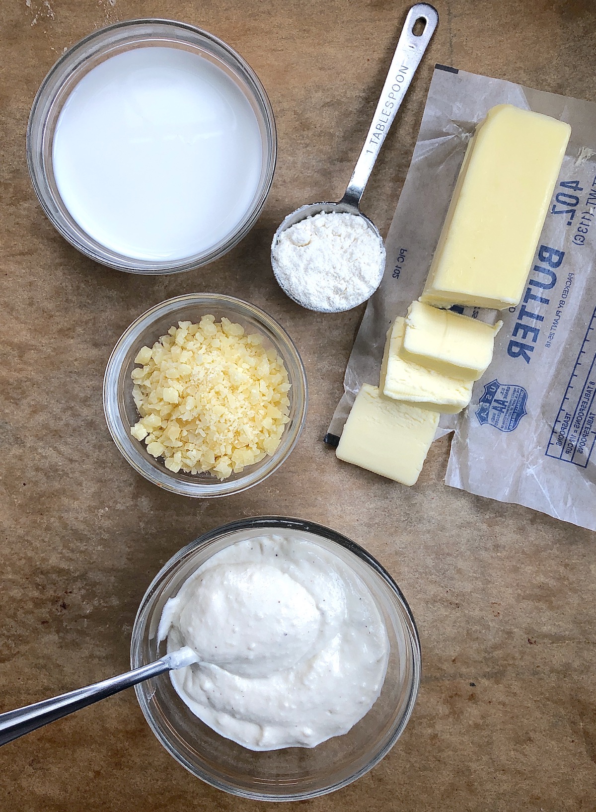Ingredients for creamy cheesy sauce, including skim milk, grated Asiago cheese, butter, and flour.