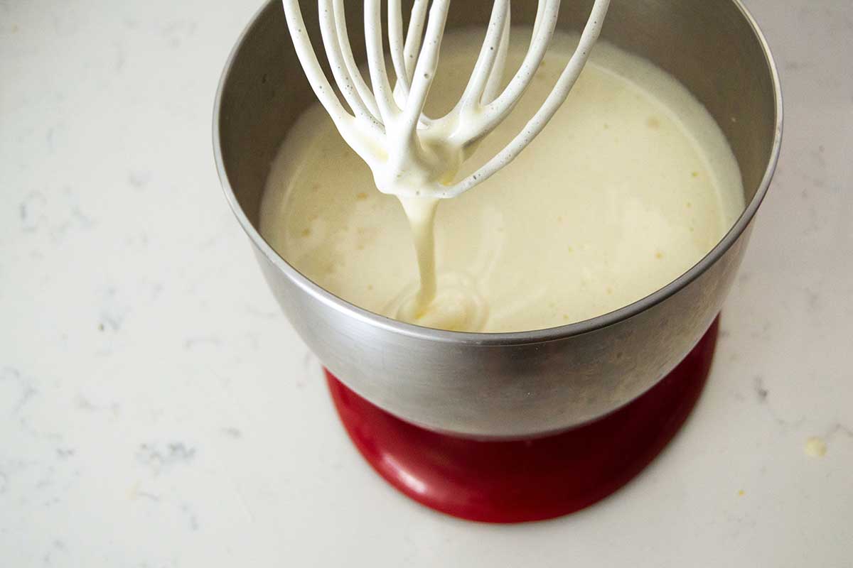 Stand mixer with whisk trailing thick batter into bowl