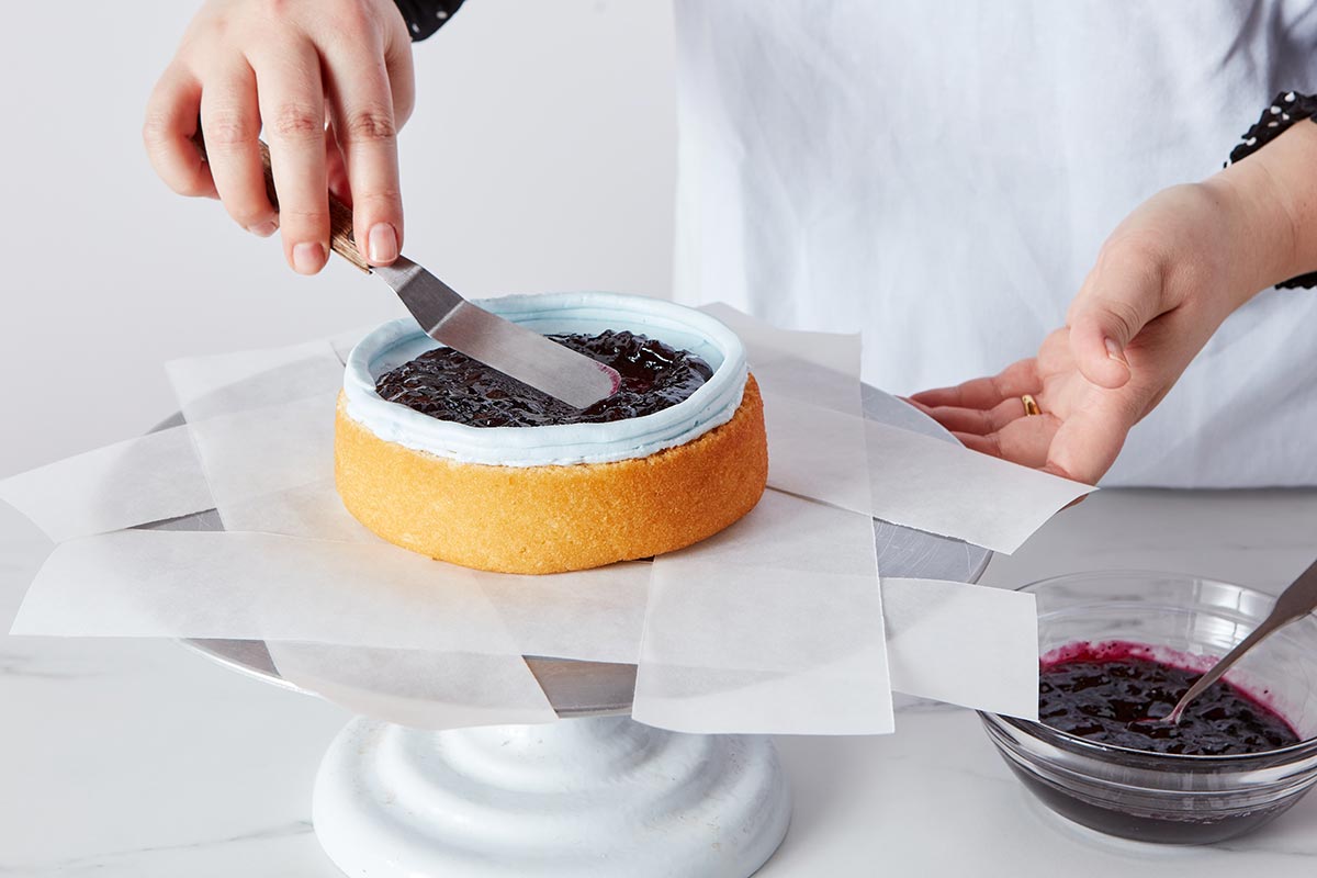 Adding filling to cake layer with piped frosting dam