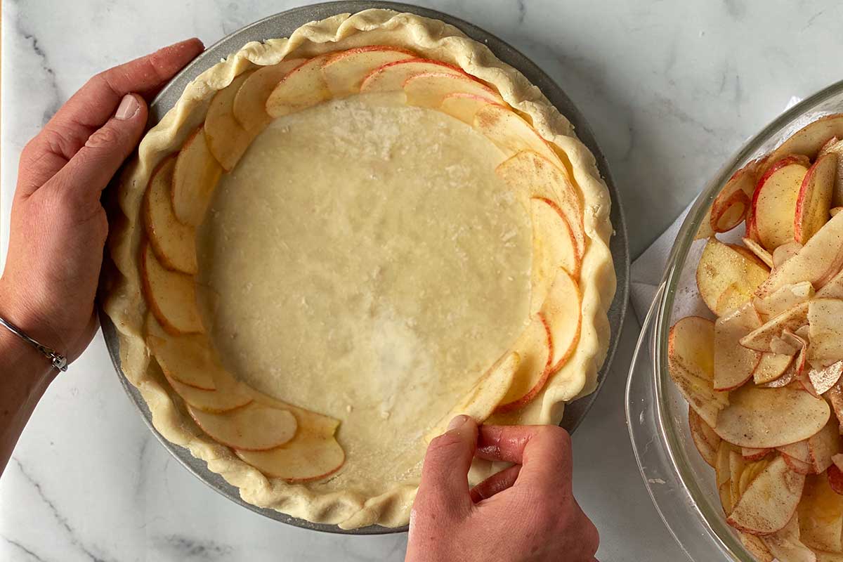 A baker's hands assembling a rose apple pie