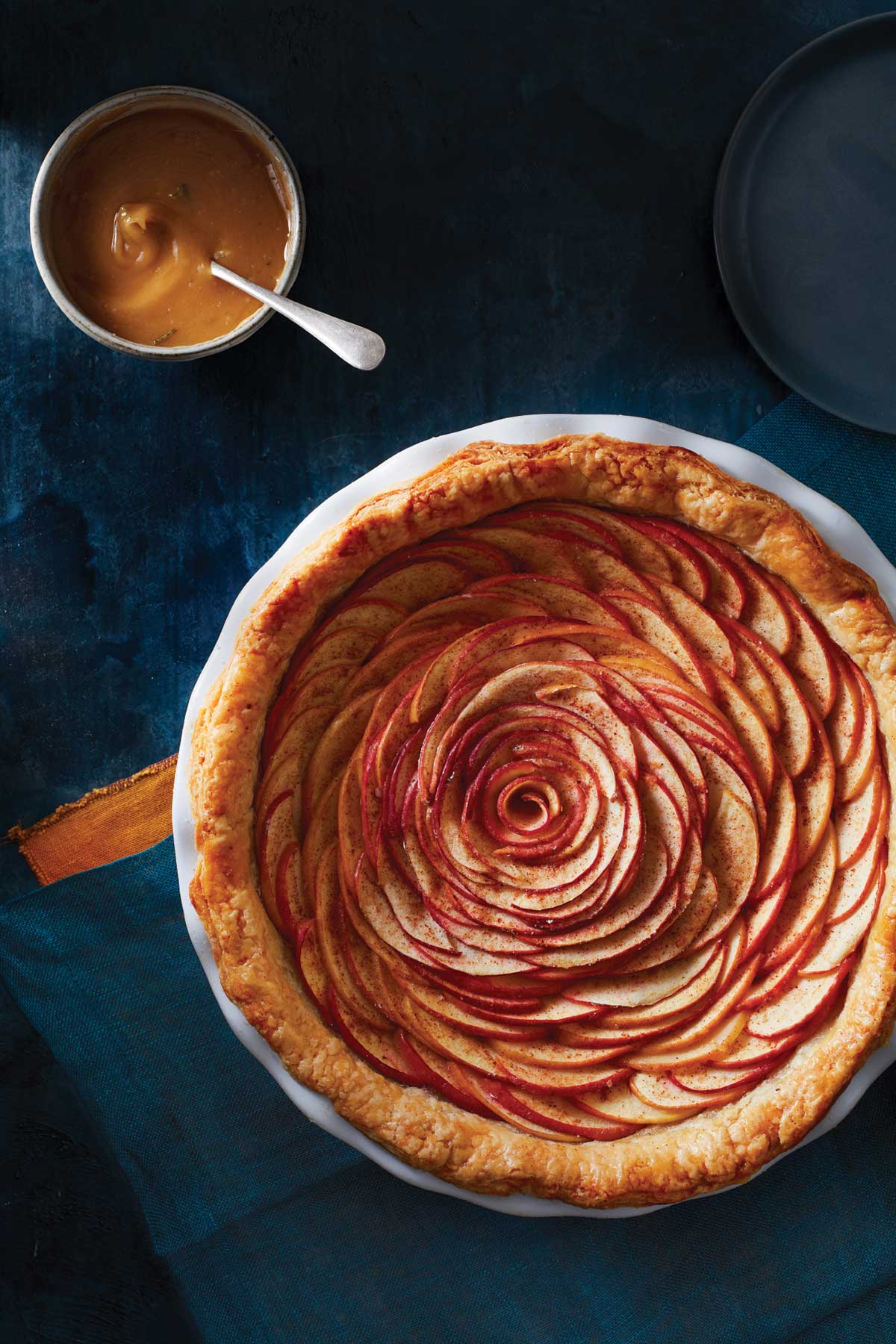 A rose apple pie next to a cup of coffee