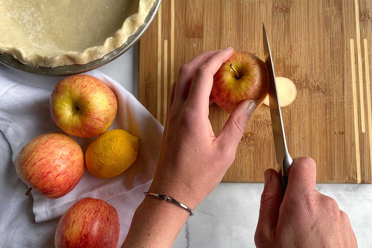 A baker about to slice into an apple using a sharp knife