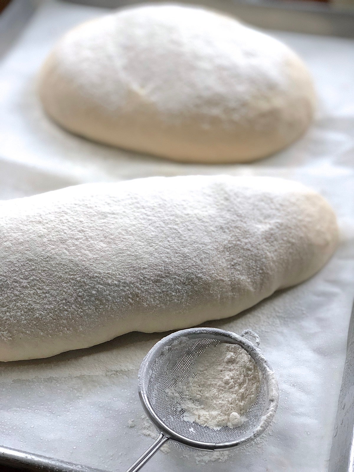 Risen loaves of sourdough bread dusted with flour.