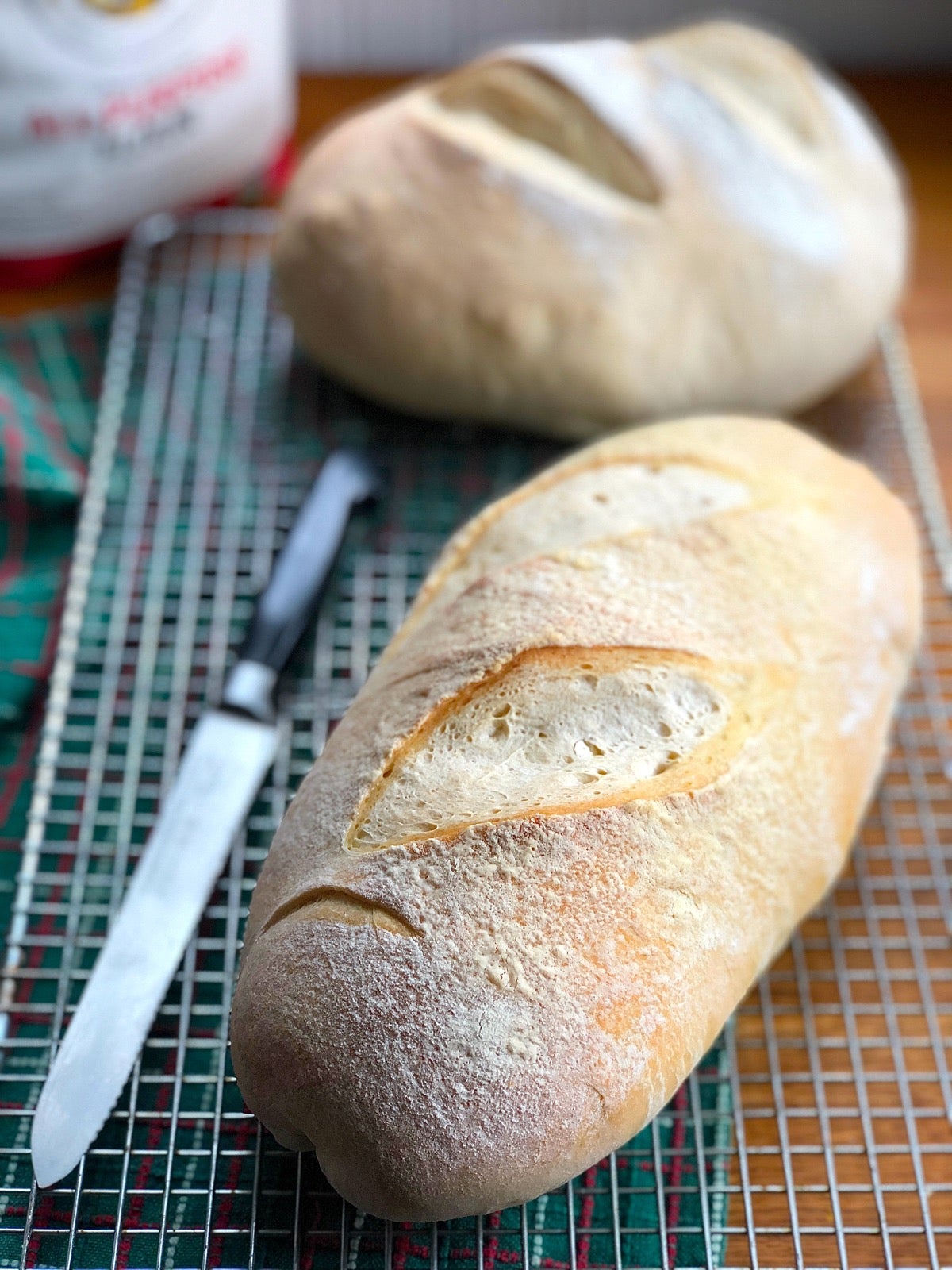 Two loaves of sourdough bread on a cooling rack, ready to slice.