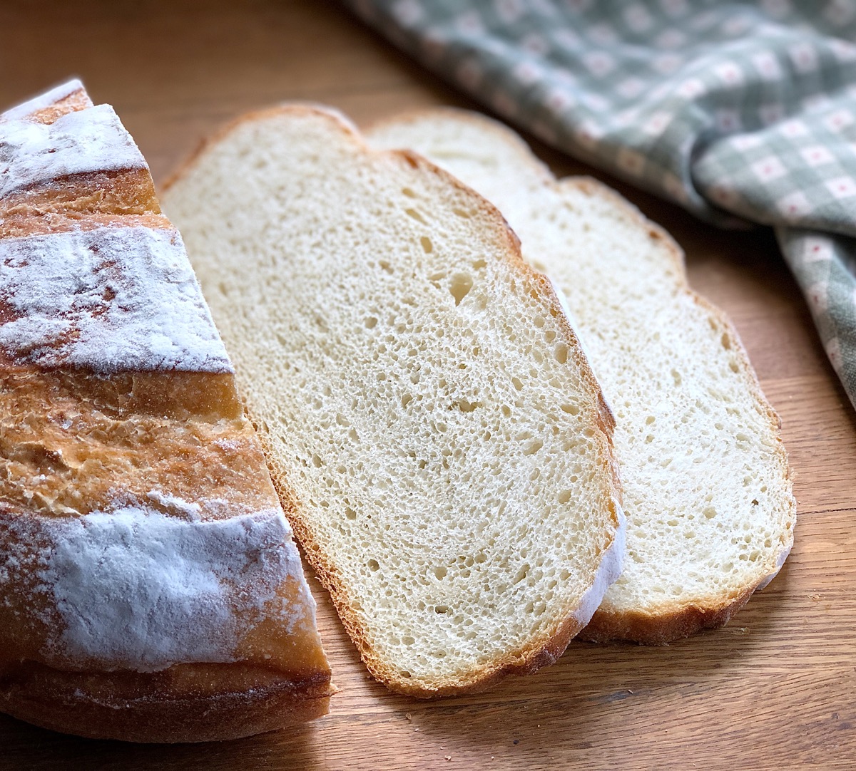 Round loaf of Rustic Sourdough Bread, sliced on a cutting board.