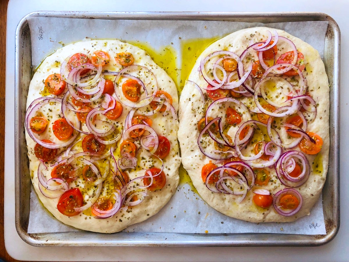 Two focaccias, one made partially with rye flour, topped with vegetables, risen, and ready to go into the oven.