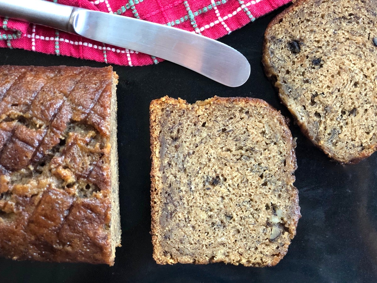 Whole Grain Banana Bread made with rye flour, loaf plus one slice o n a cutting board.