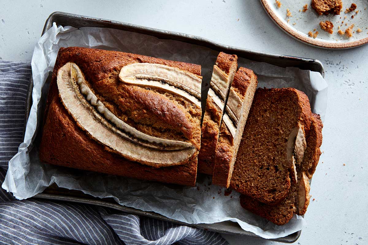 A loaf of rye banana bread fresh from the oven with a banana sliced on top