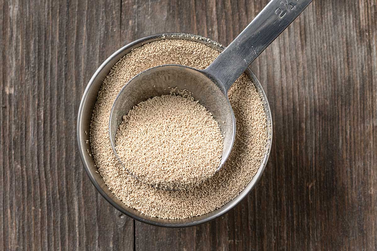 A measuring spoon in a small bowl of yeast