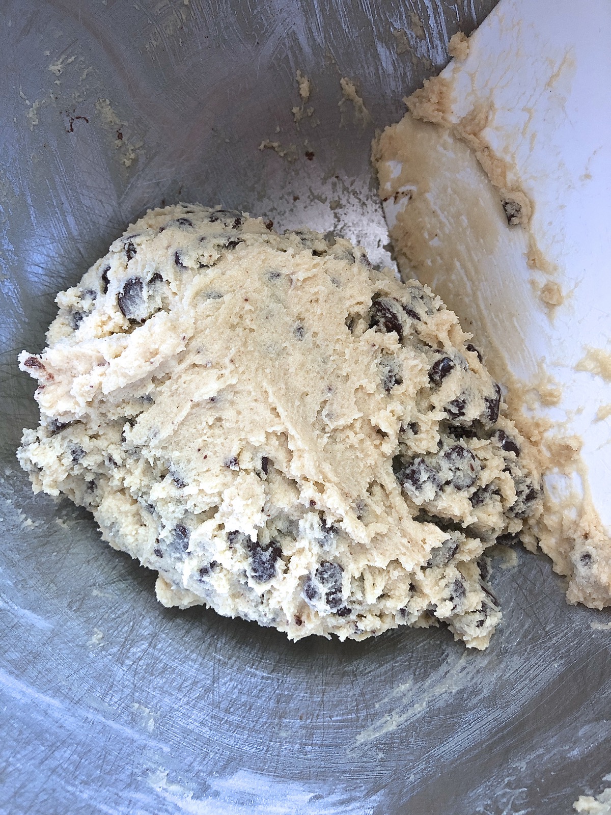 Chocolate chip cookie dough scraped into a ball in the center of the mixing bowl.