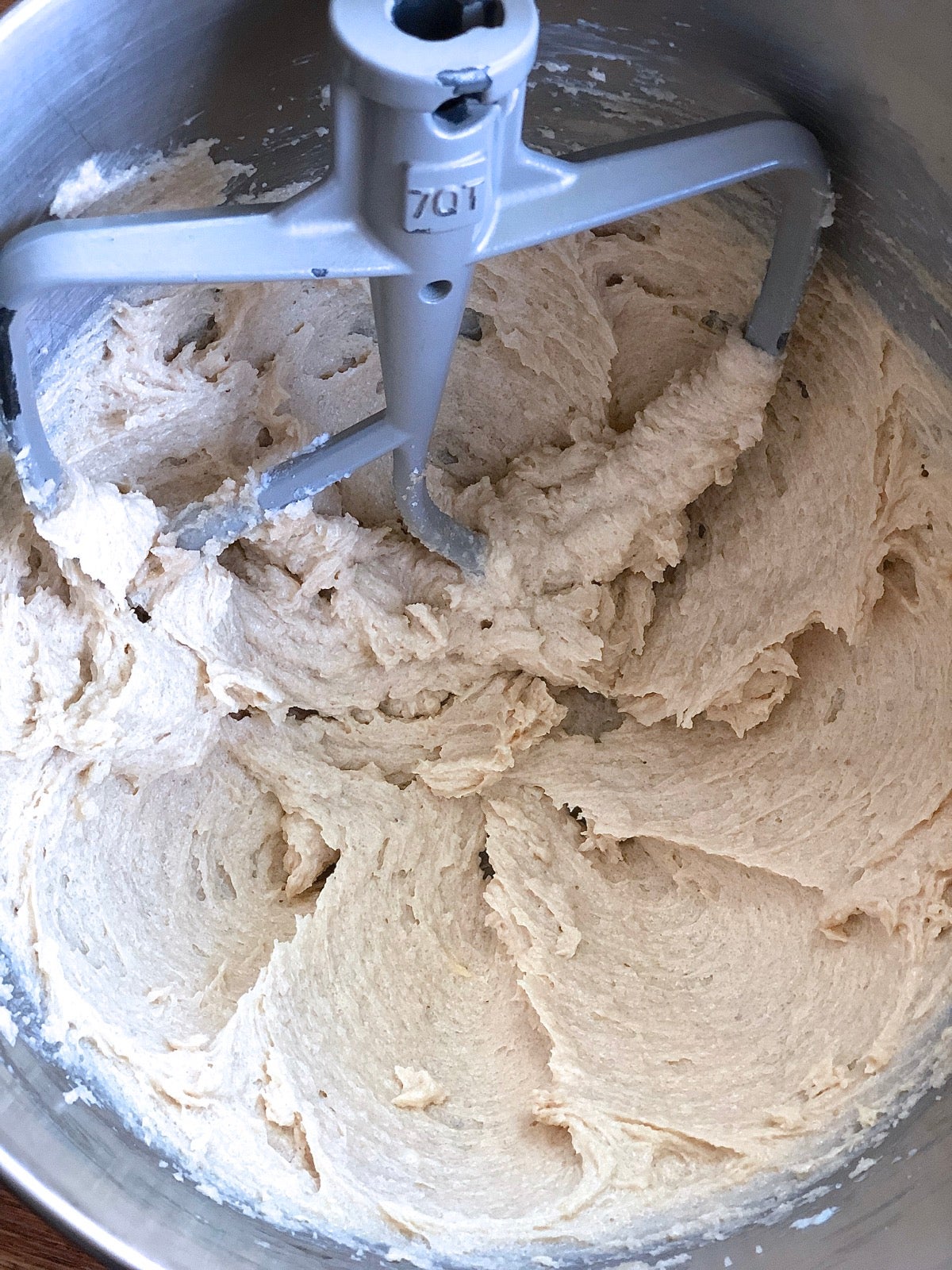 Chocolate chip cookie dough being mixed in a stainless steel bowl.