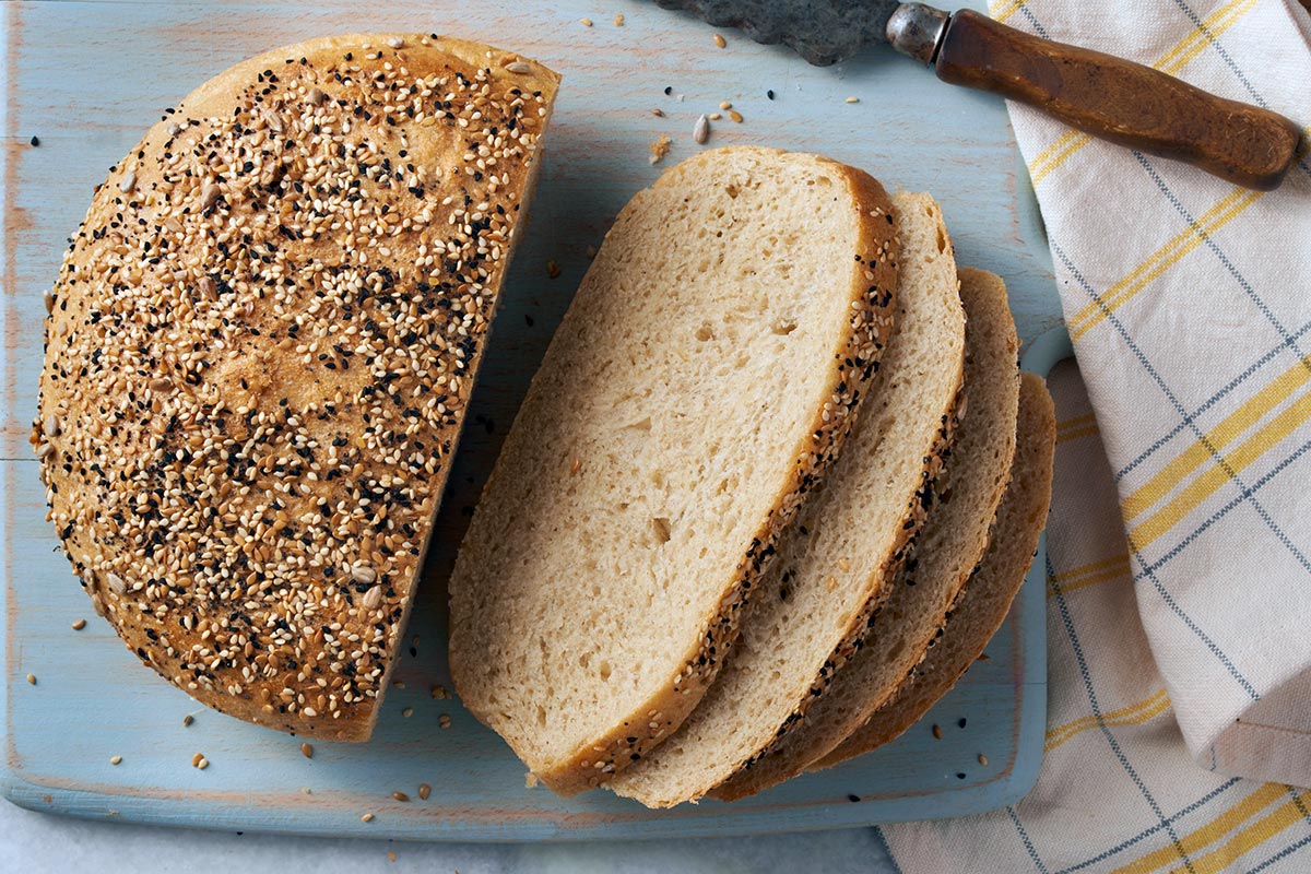 A loaf of chewy semolina rye bread with a few slices cut