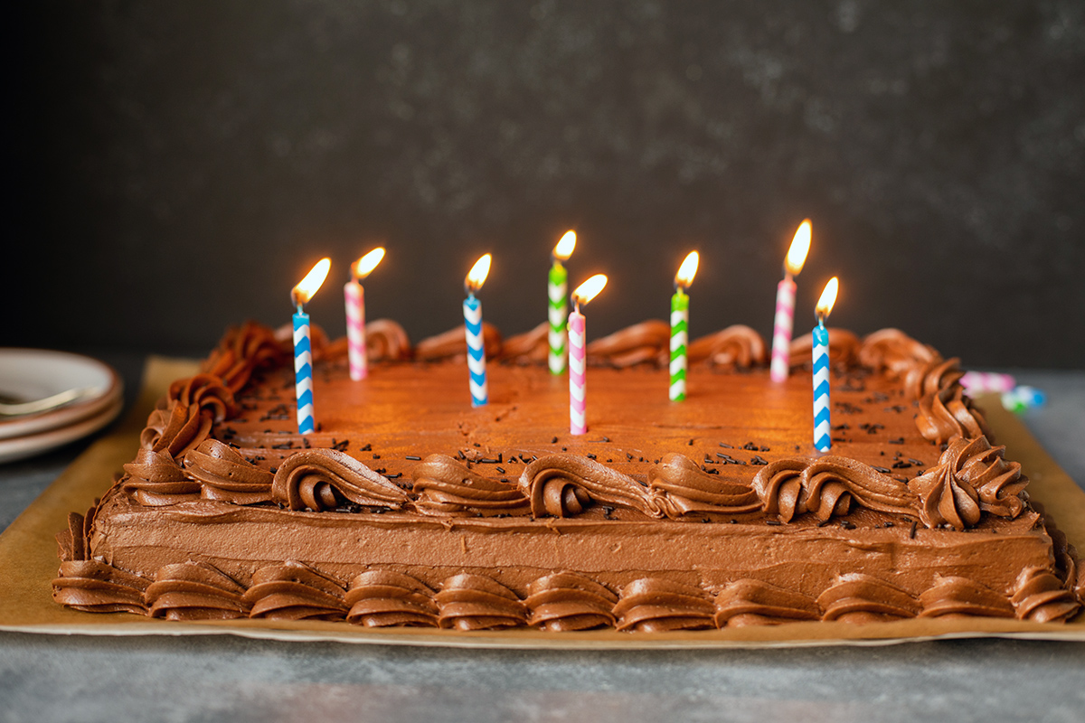 A chocolate sheet cake topped with lit birthday candles