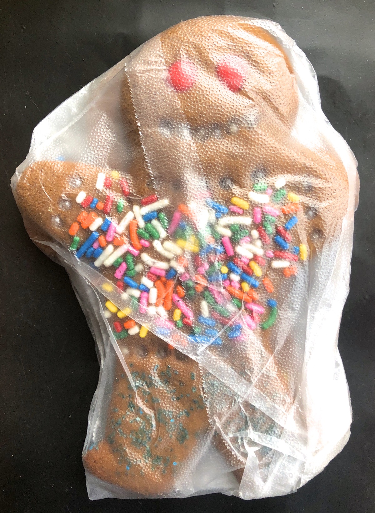 Decorated gingerbread man wrapped in plastic.