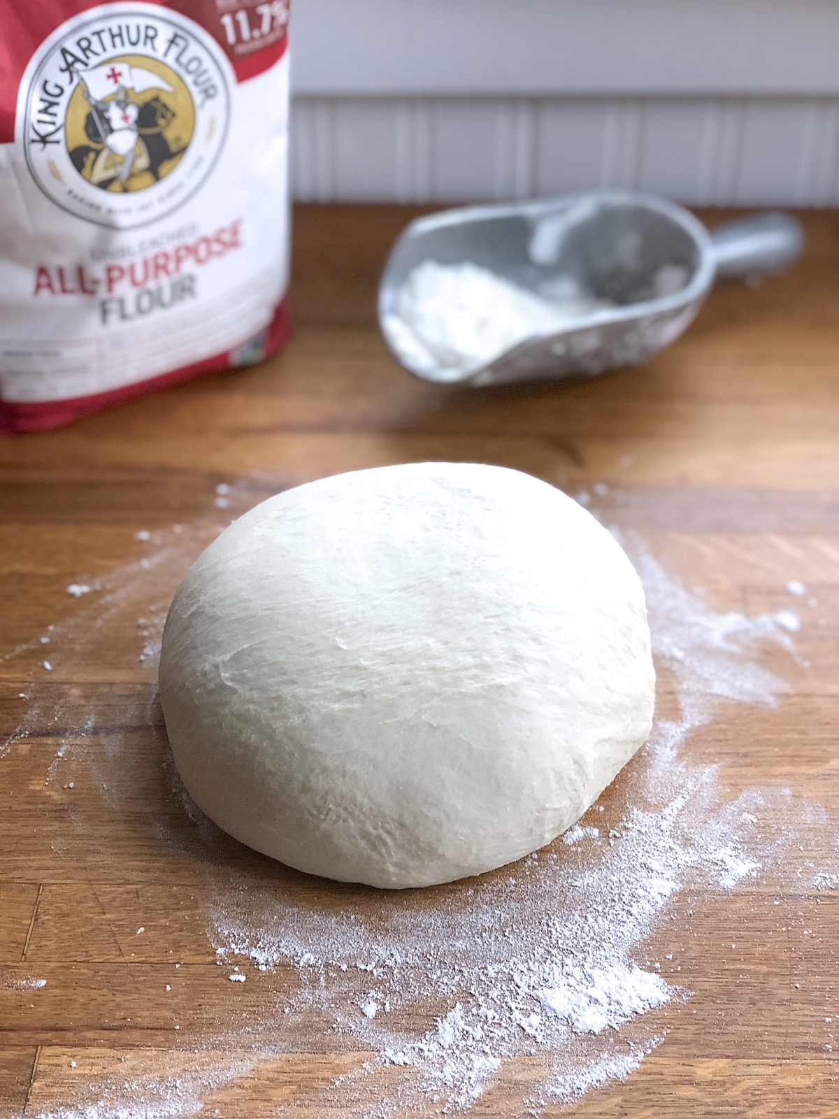 A smooth ball of fully kneaded dough on a floured tabletop.