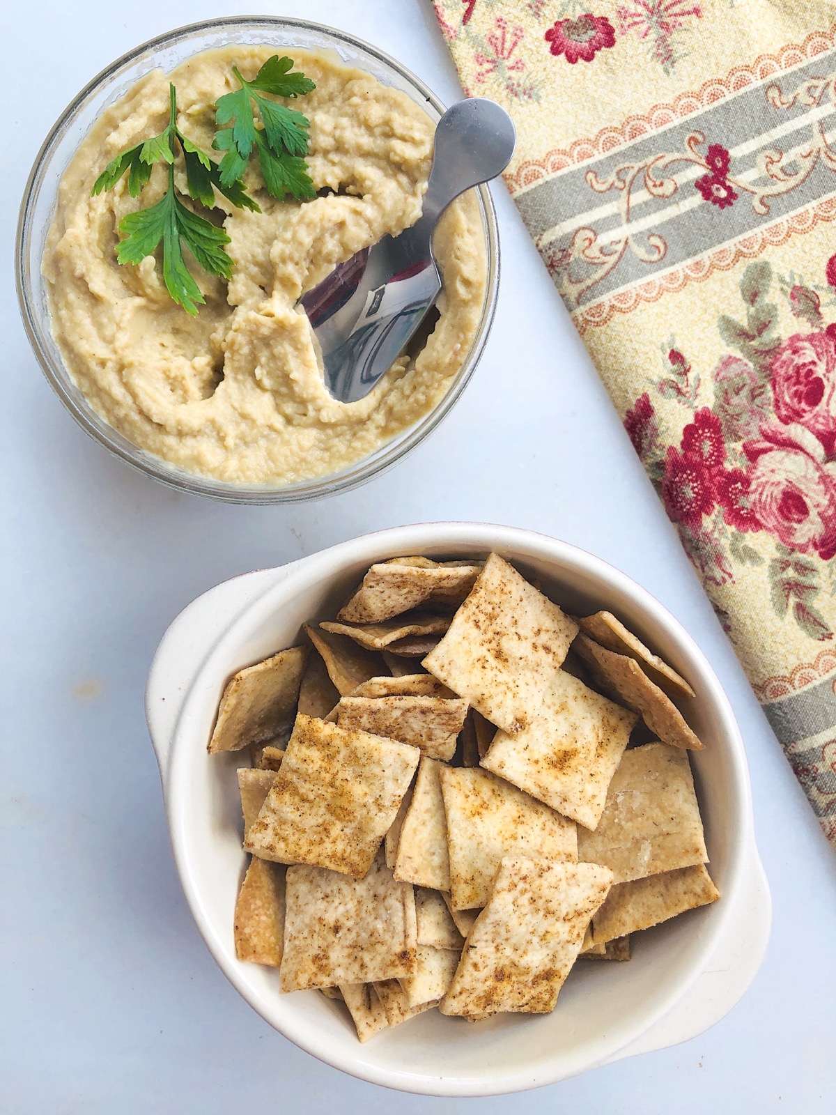 Sourdough crackers in a bowl, bowl of hummus alongside.