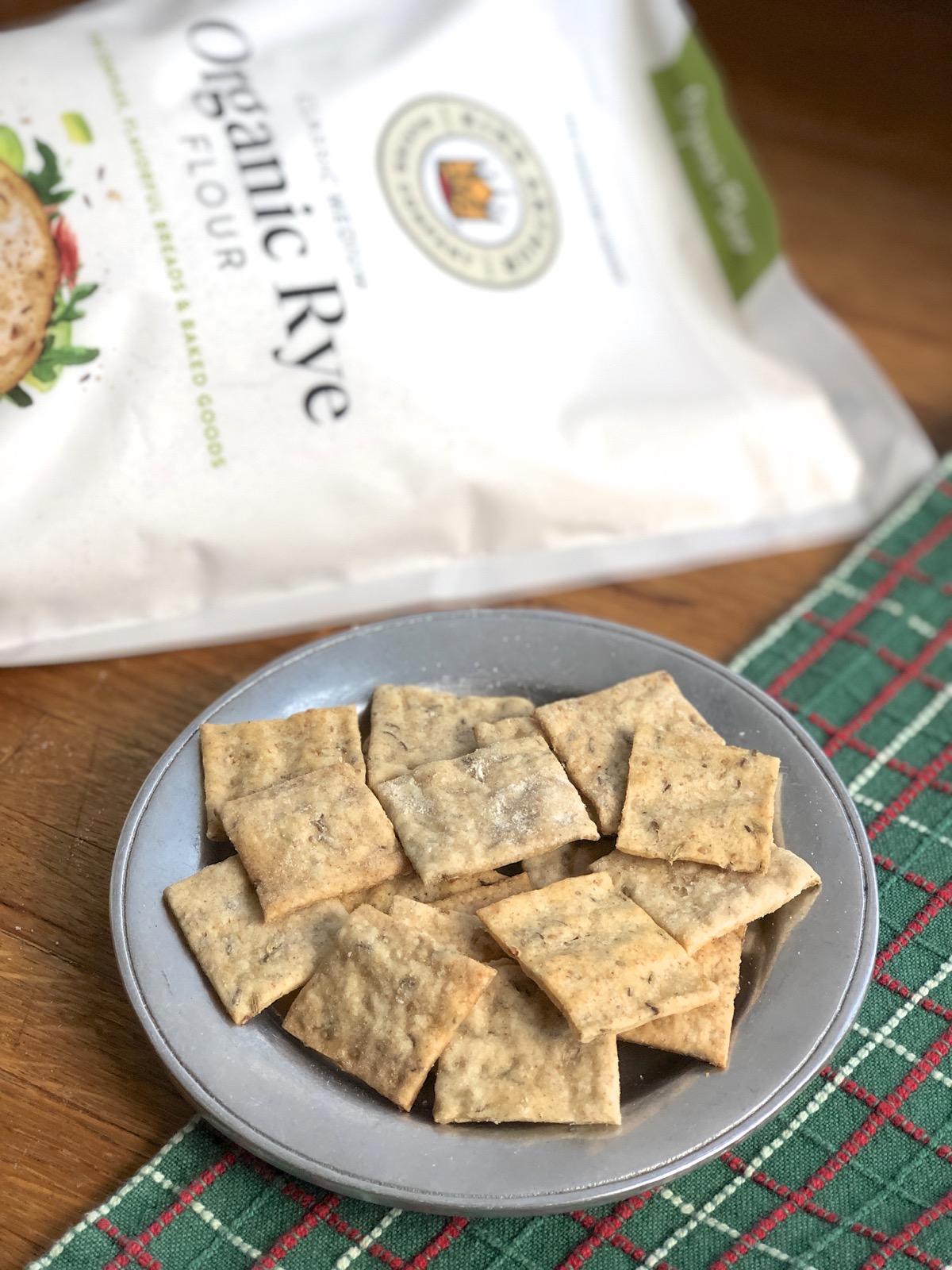 Sourdough crackers on a plate in front of a bag of rye flour.