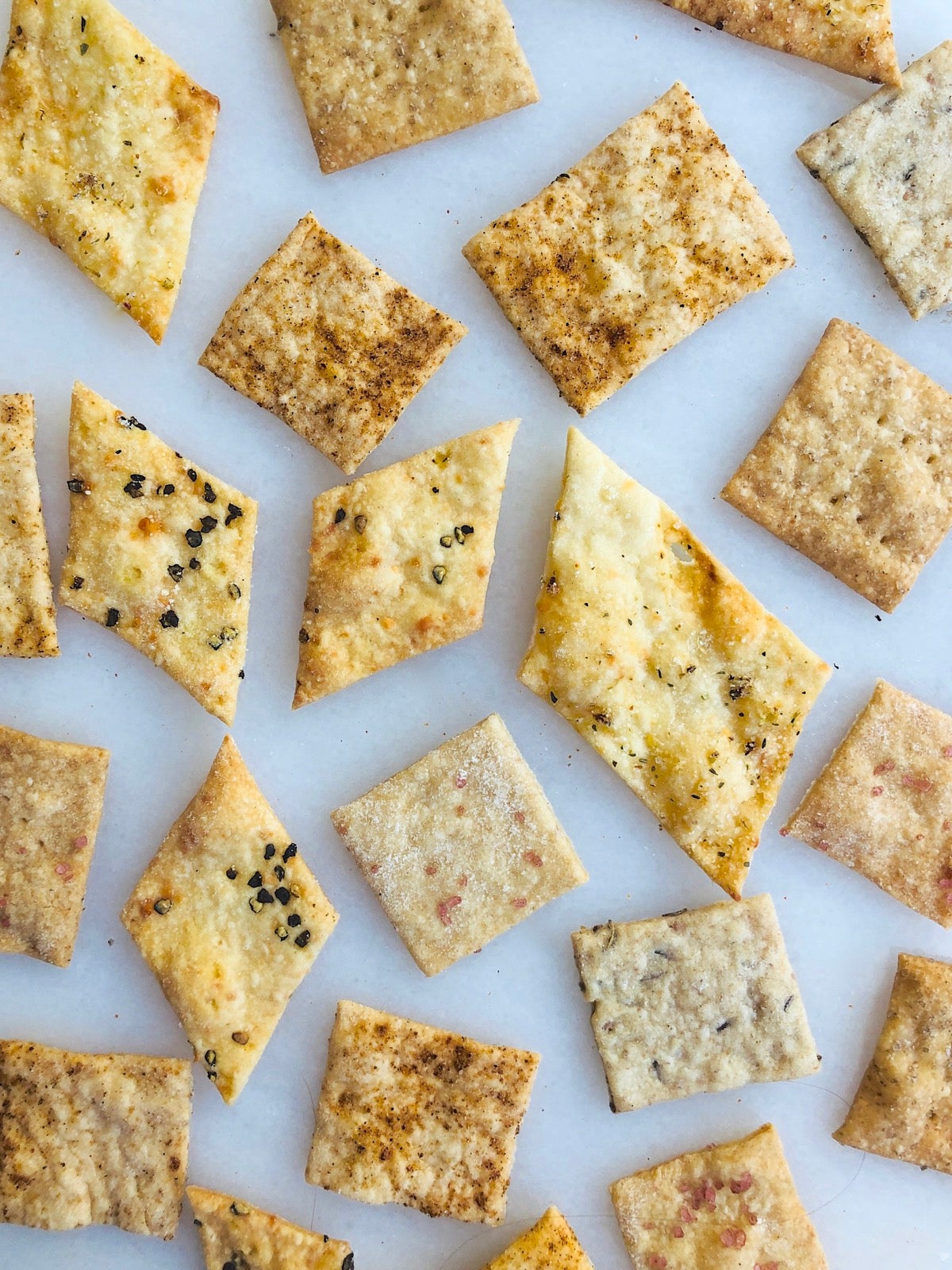 Assorted sourdough crackers on a white marble serving board.