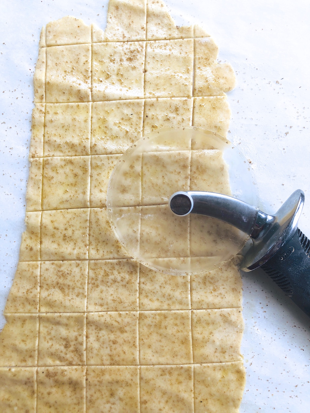 Sourdough cracker dough rolled out and cut into small squares using a rolling pizza wheel.