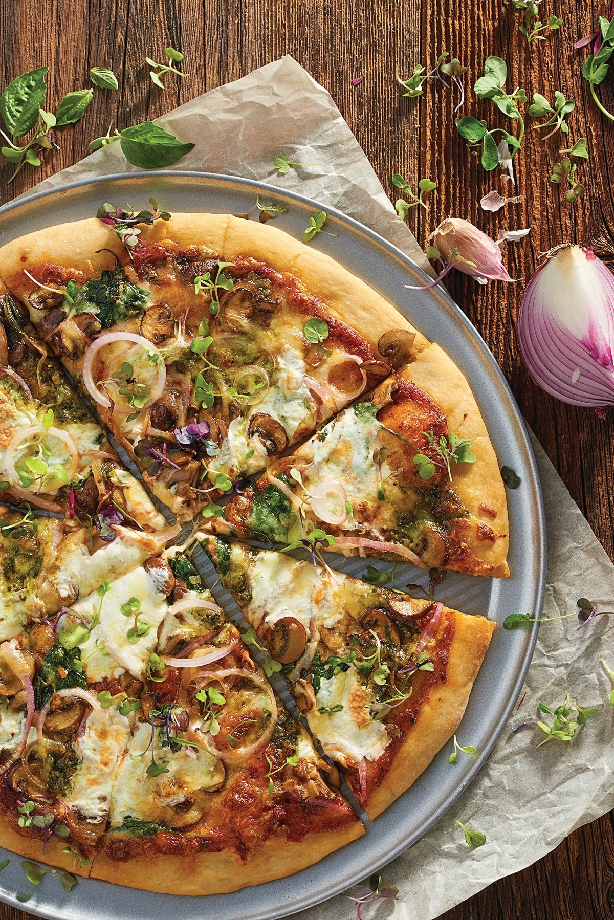 Sourdough pizza crust topped with onions, tomato sauce, mushrooms, cheese, and fresh herbs.