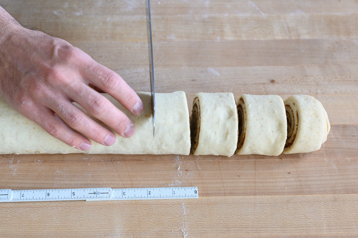 Cutting sourdough cinnamon bun cylinder.