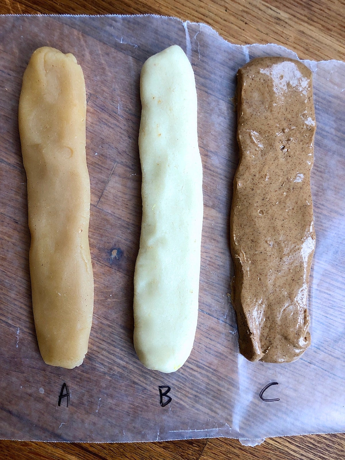 Three different flattened logs of stollen filling side by side: packaged almond paste, homemade almond paste, and sweetened almond butter.