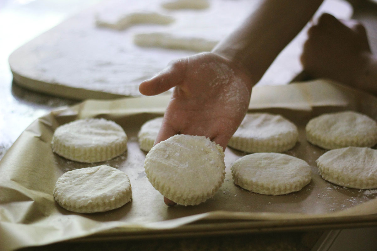 Unbaked biscuits being placed on baking sheet