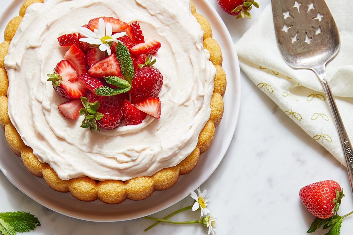 A strawberry mousse cake topped with strawberries and daisies