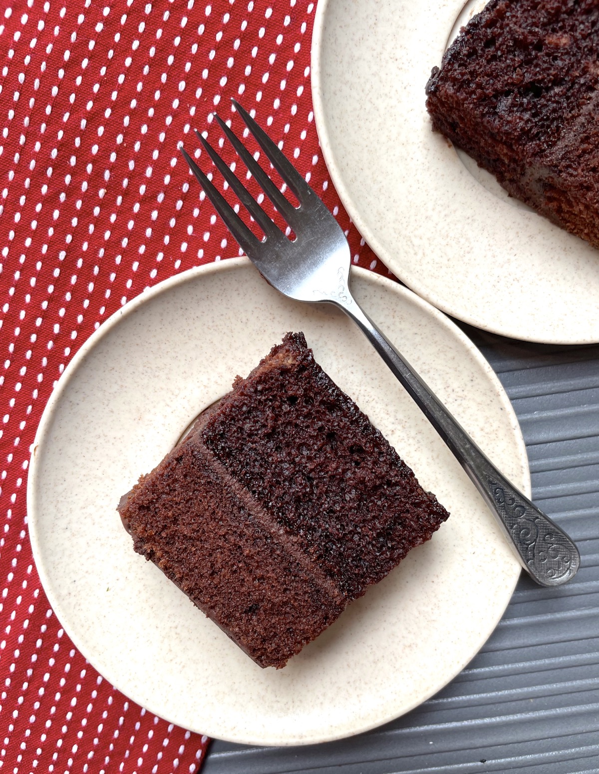 Slice of double layer chocolate cake with chocolate frosting on a plate.
