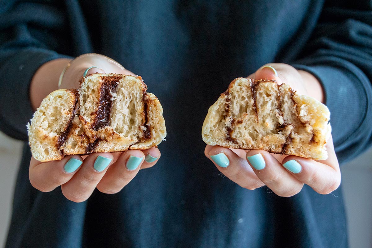 Hands holding two cinnamon rolls 