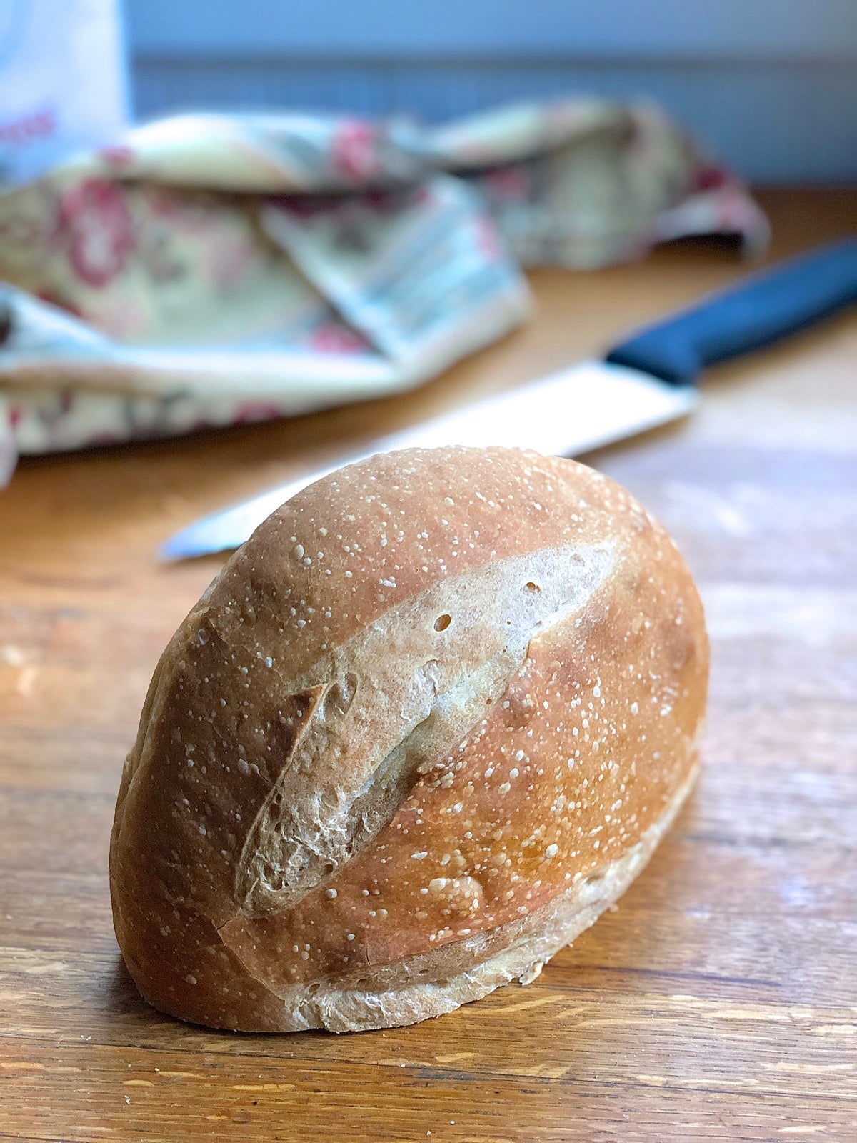 Large round loaf cut in half and stored cut-side down on a countertop.