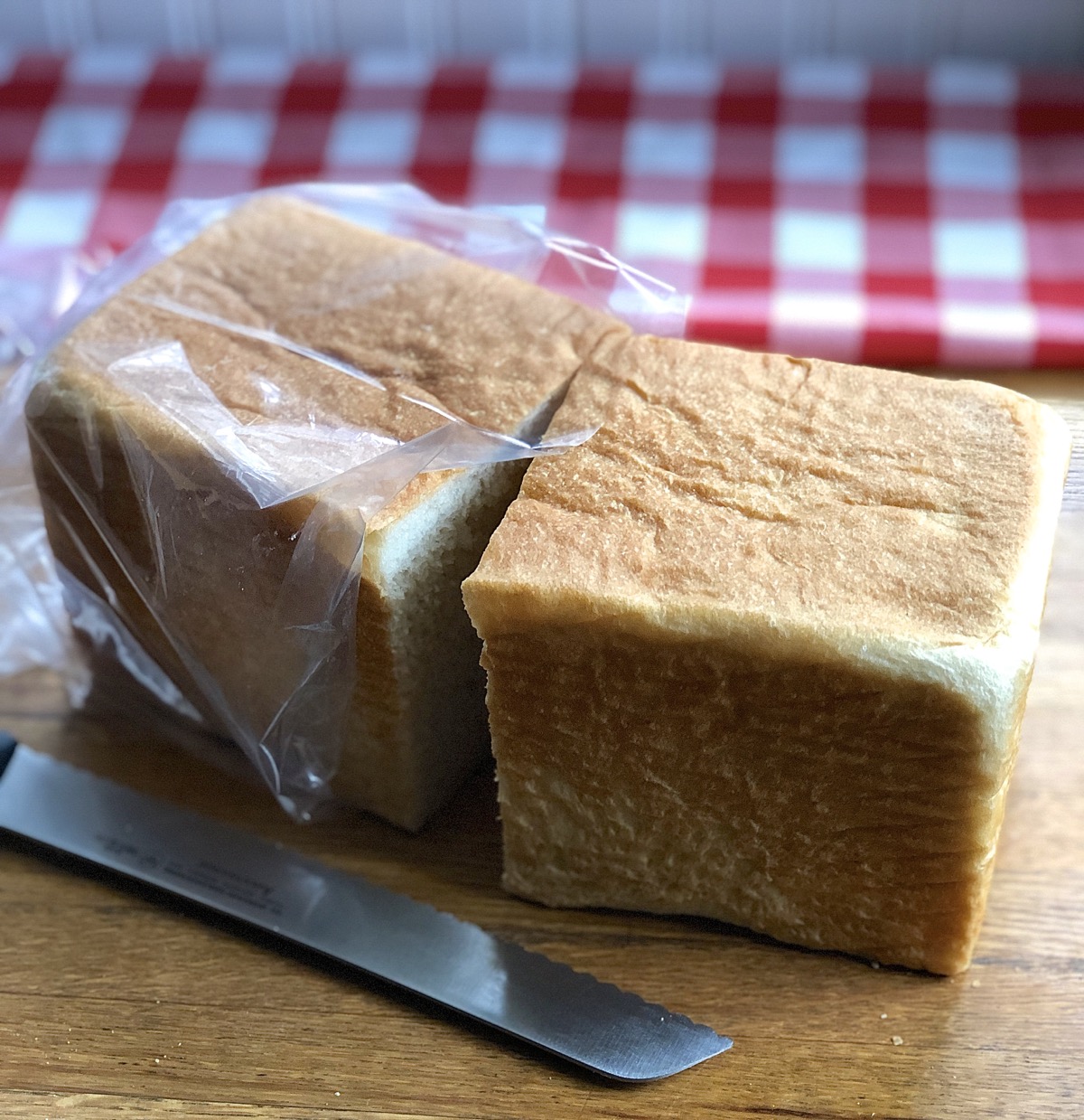 Loaf of sandwich bread cut in half, one half in plastic bag.