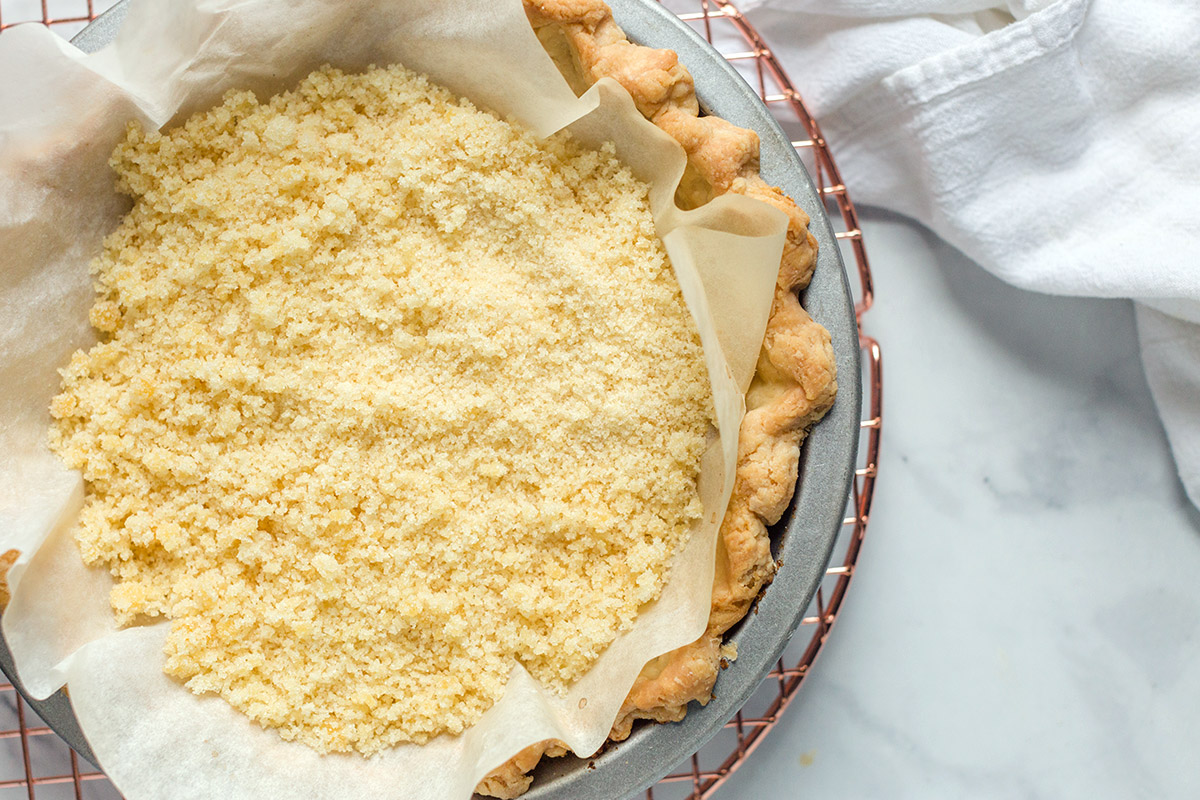 A blind baked pie crust that’s started to turn golden brown and is filled with toasted sugar