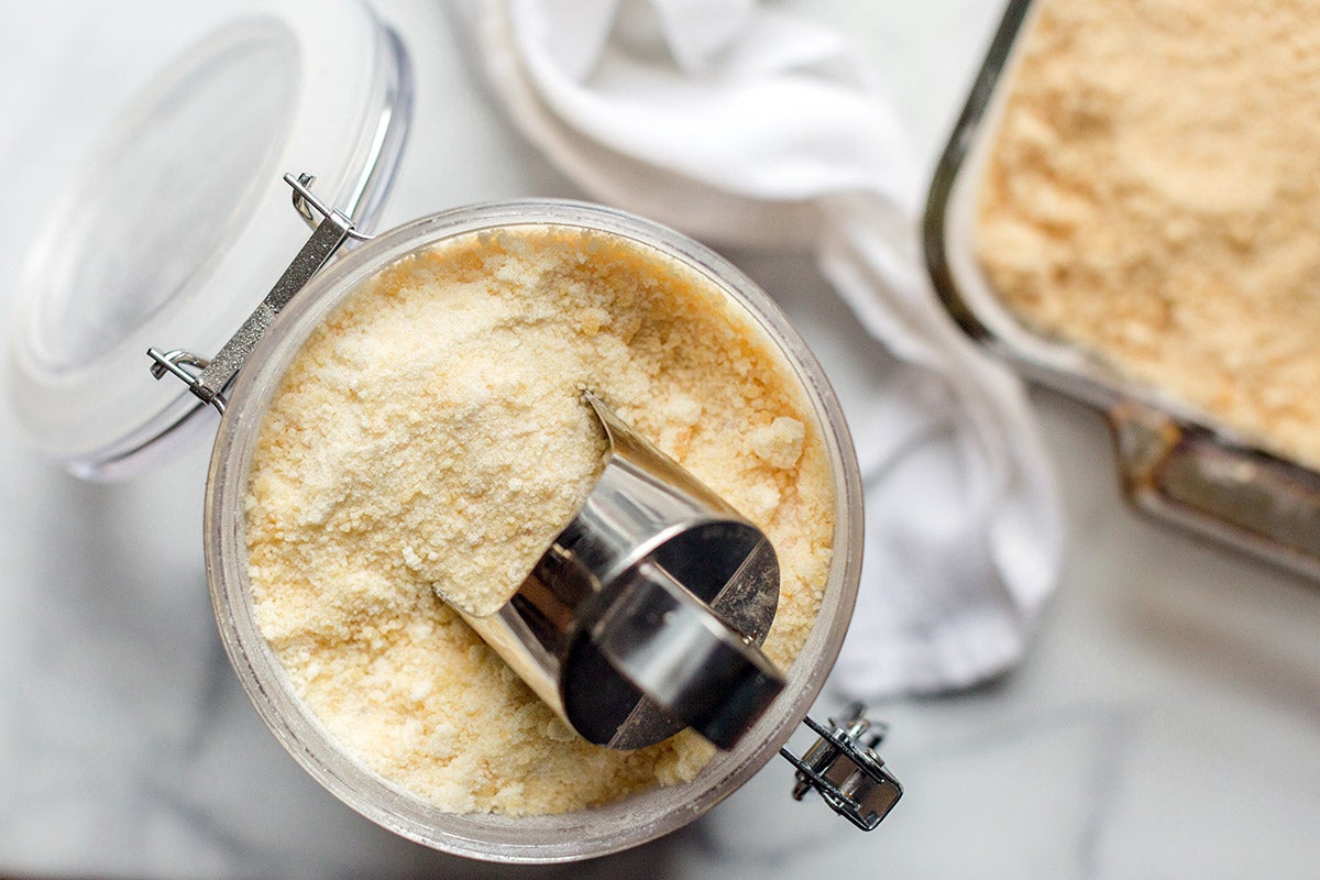 A container of toasted sugar with a scoop and a pan of toasted sugar on the kitchen table