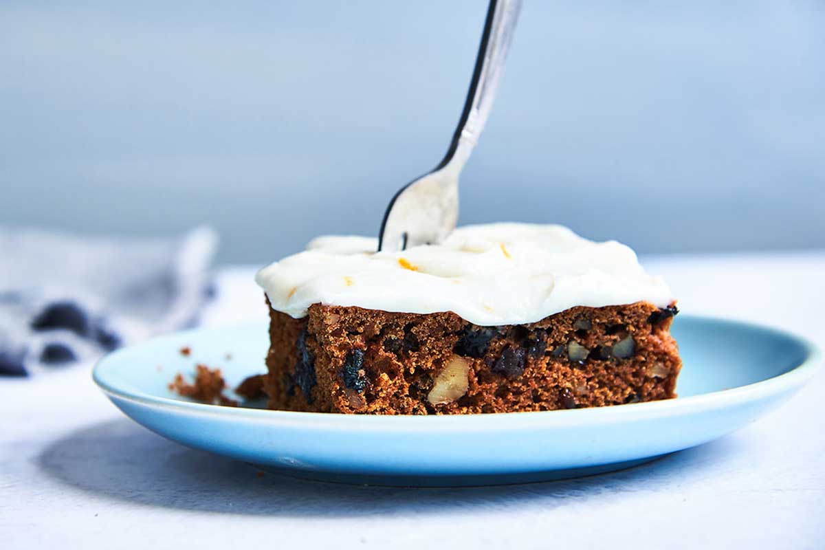 A slice of tomato soup spice cake on a plate topped with cream cheese frosting