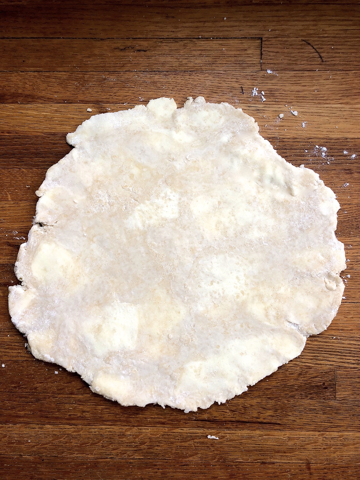 Pie crust rolled into a round, with flattened "sheetlets" of butter visible.