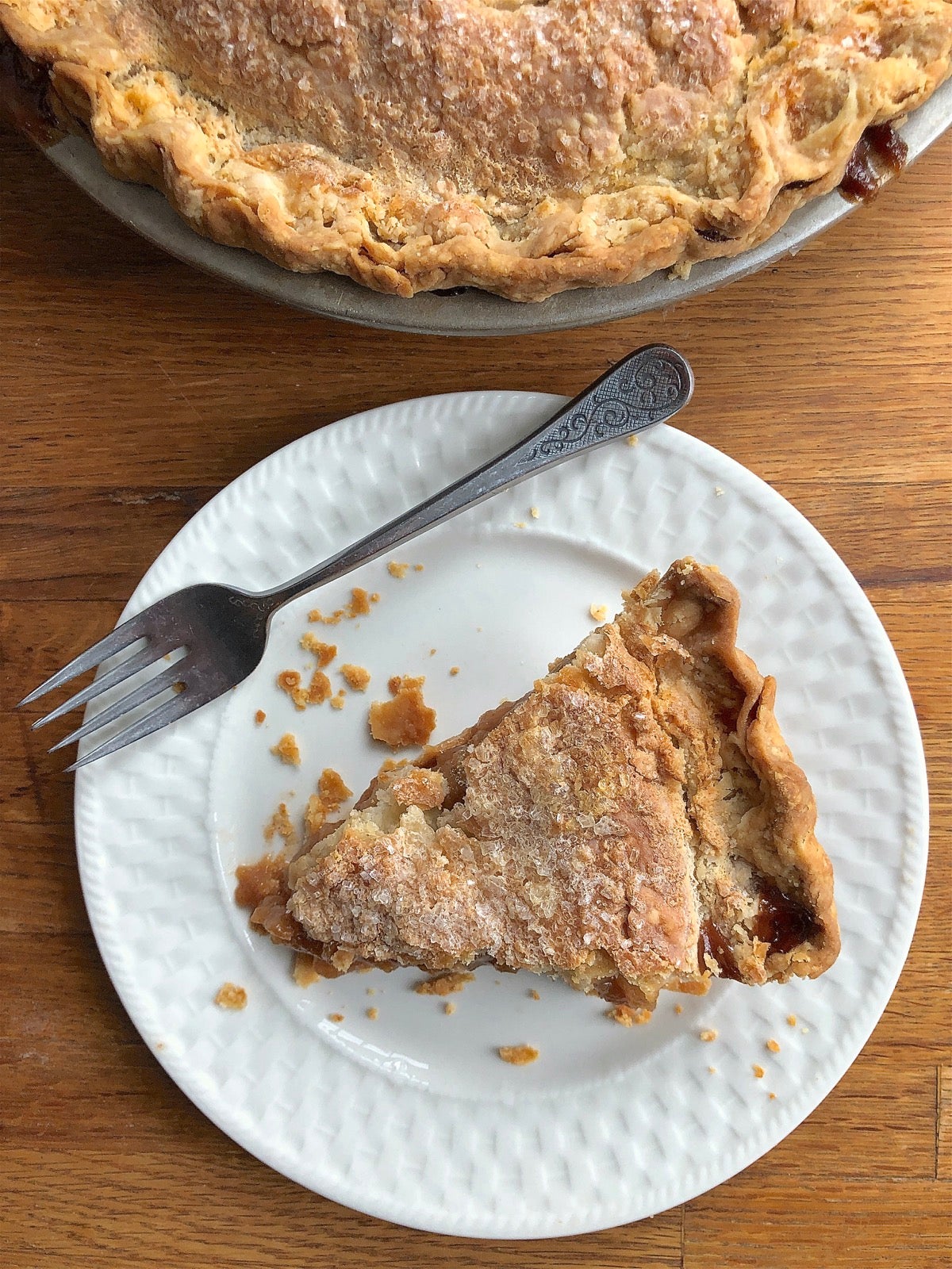 Slice of pie on a plate, edge of whole pie in pan.